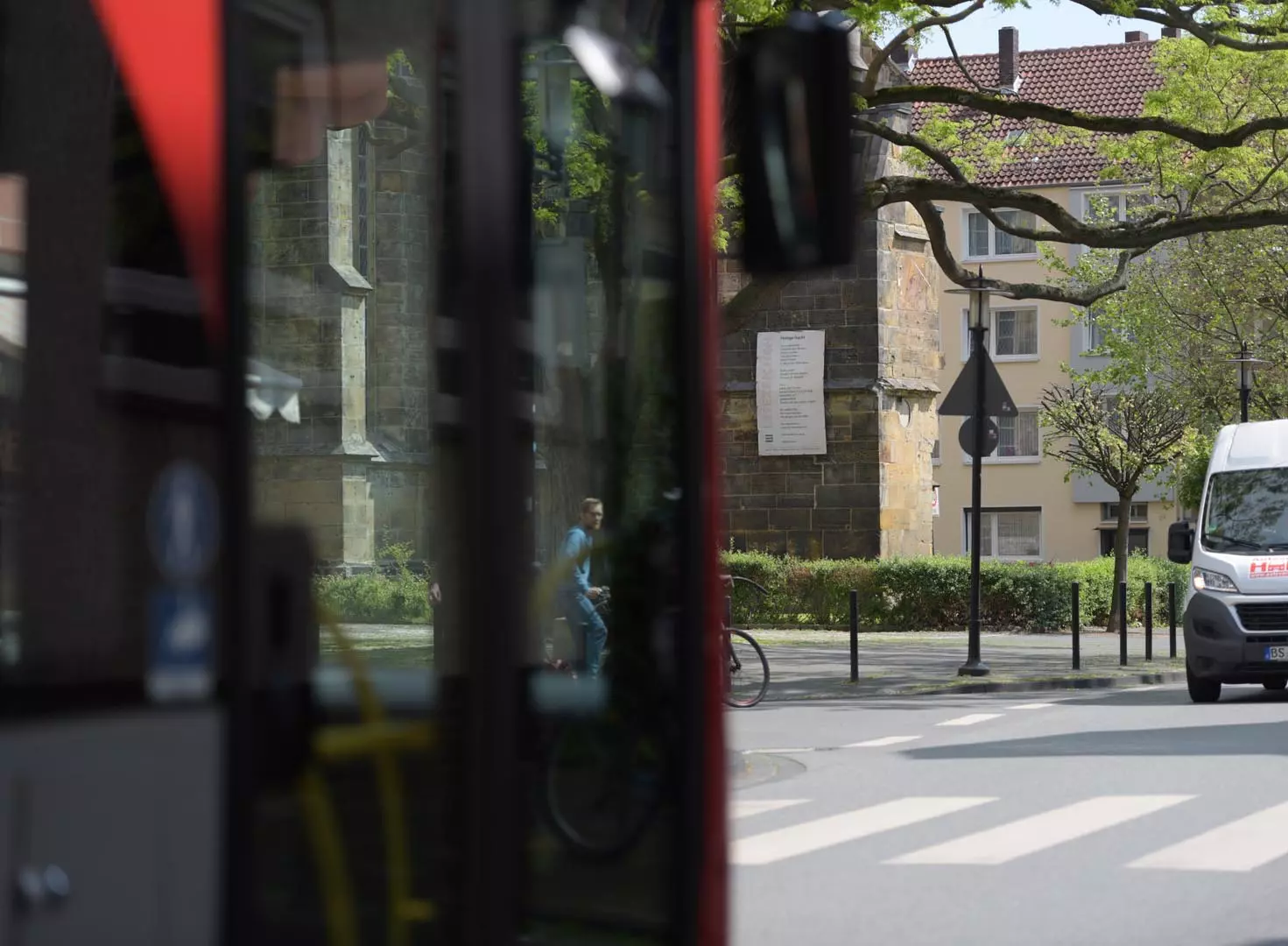 An der Fassade der Lambertikirche hängt ein Plakat der "Lesezeichen", im Vordergrund fährt ein Stadtbus vorbei