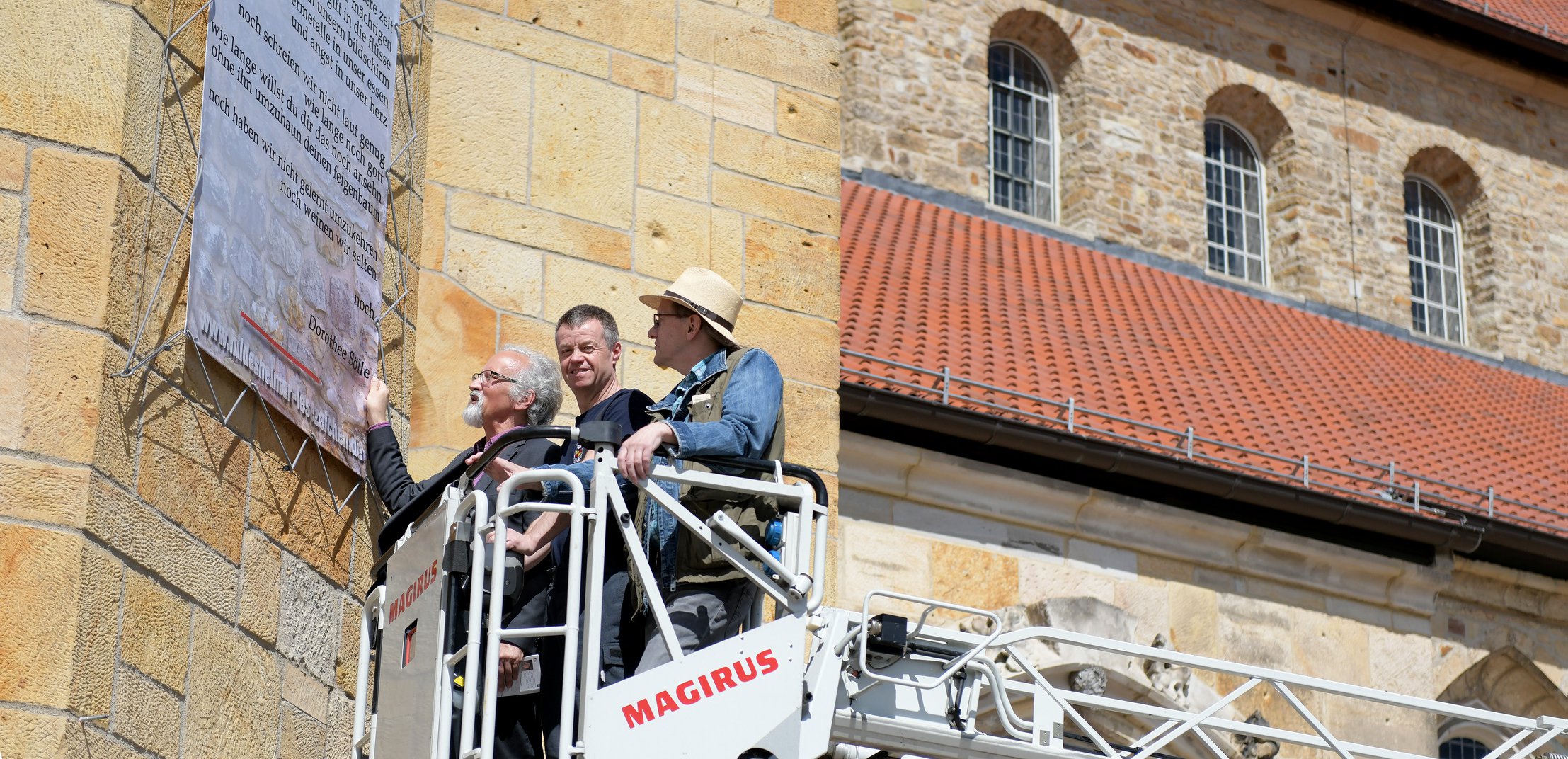 Jo Köhler bringt gemeinsam mit zwei Mitstreitern ein Gedichtbanner an der Fassade der Michaeliskirche an