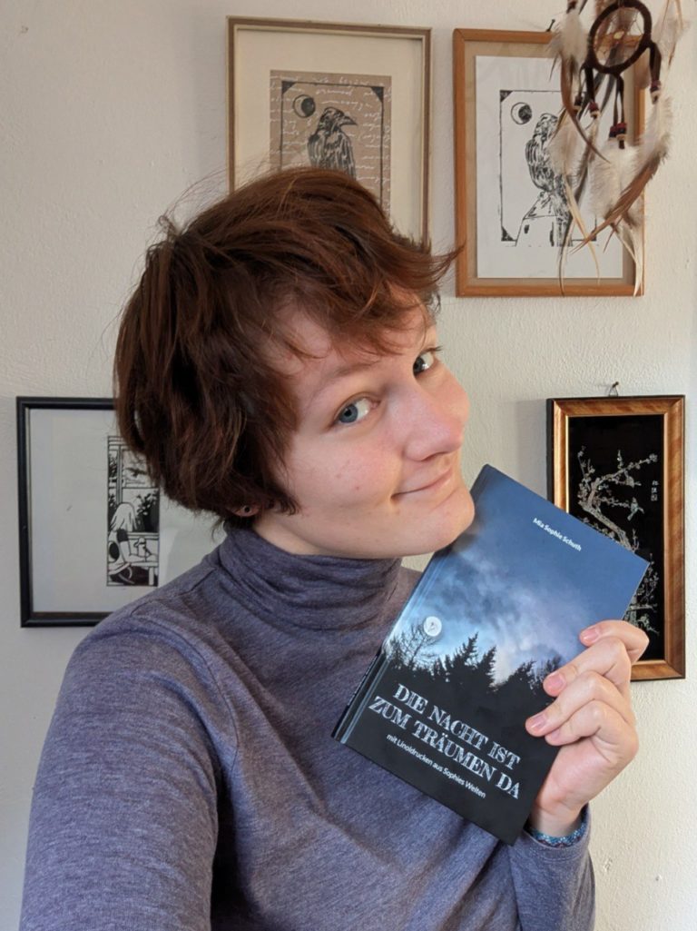 Ein Porträt-Foto von Mia Sophie Schuth, die ihr Buch “Die Nacht ist zum Träumen da” in der Hand hält.