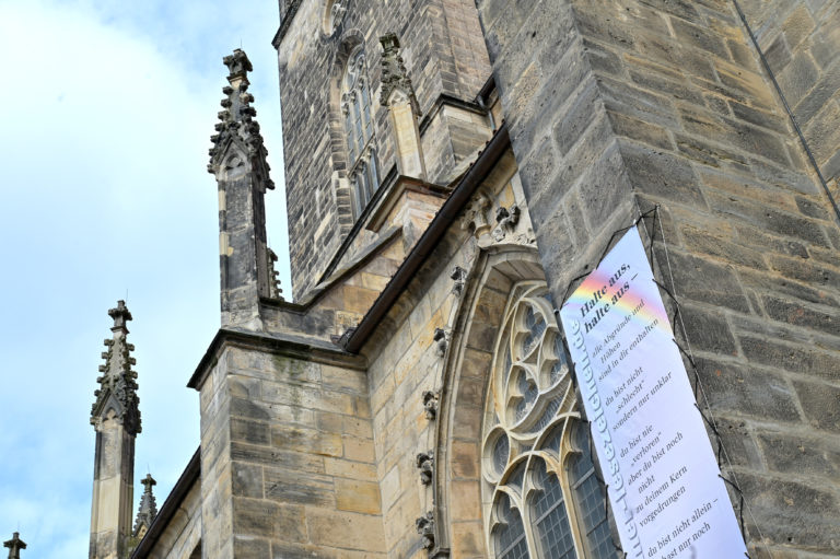 Das Gedichtbanner mit dem Text "Halte aus, Halte aus" hängt an der Andreaskirche.