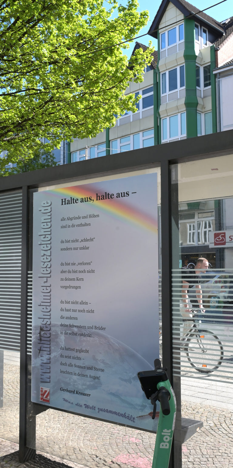 Das Gedicht "Halt aus, Halte aus-" an der Bushaltestelle "Schuhstraße". Ein E-Scooter steht angelehnt an die Bushaltestelle.